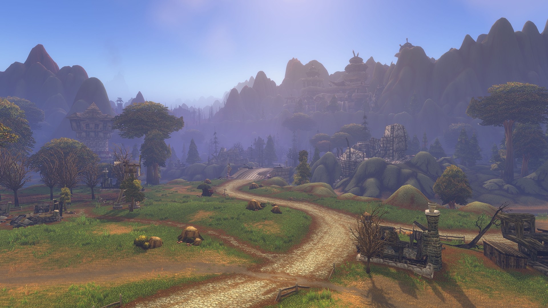 A road winds between ruined buildings, trees, and distant mountains in World of Warcraft Forever